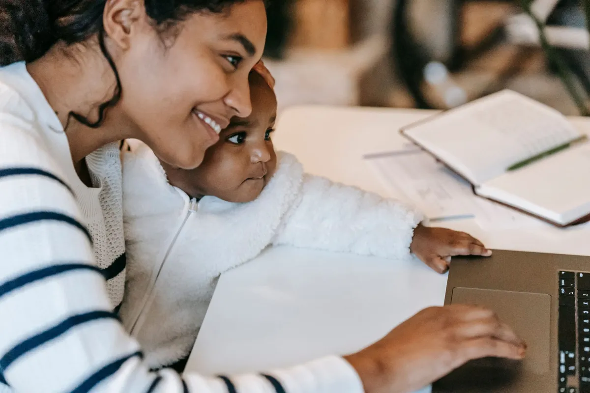 Ein berufstätiges Elternteil am Laptop zu Hause, die Kinder in der Nähe